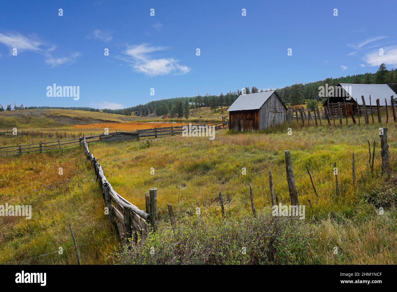Un antiguo rancho con vallas y edificios rústicos de madera en Colorado. Una escena otoñal bajo un cielo azul. Foto de stock