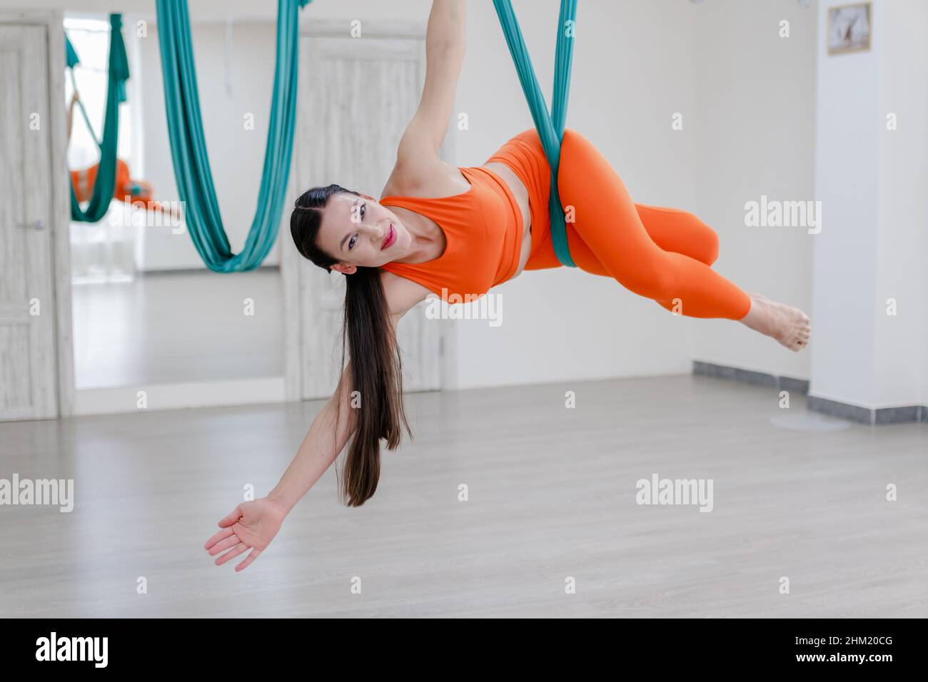 mujer morena en ropa deportiva naranja usando una hamaca azul aero yoga y  fingiendo estar dormido Fotografía de stock - Alamy