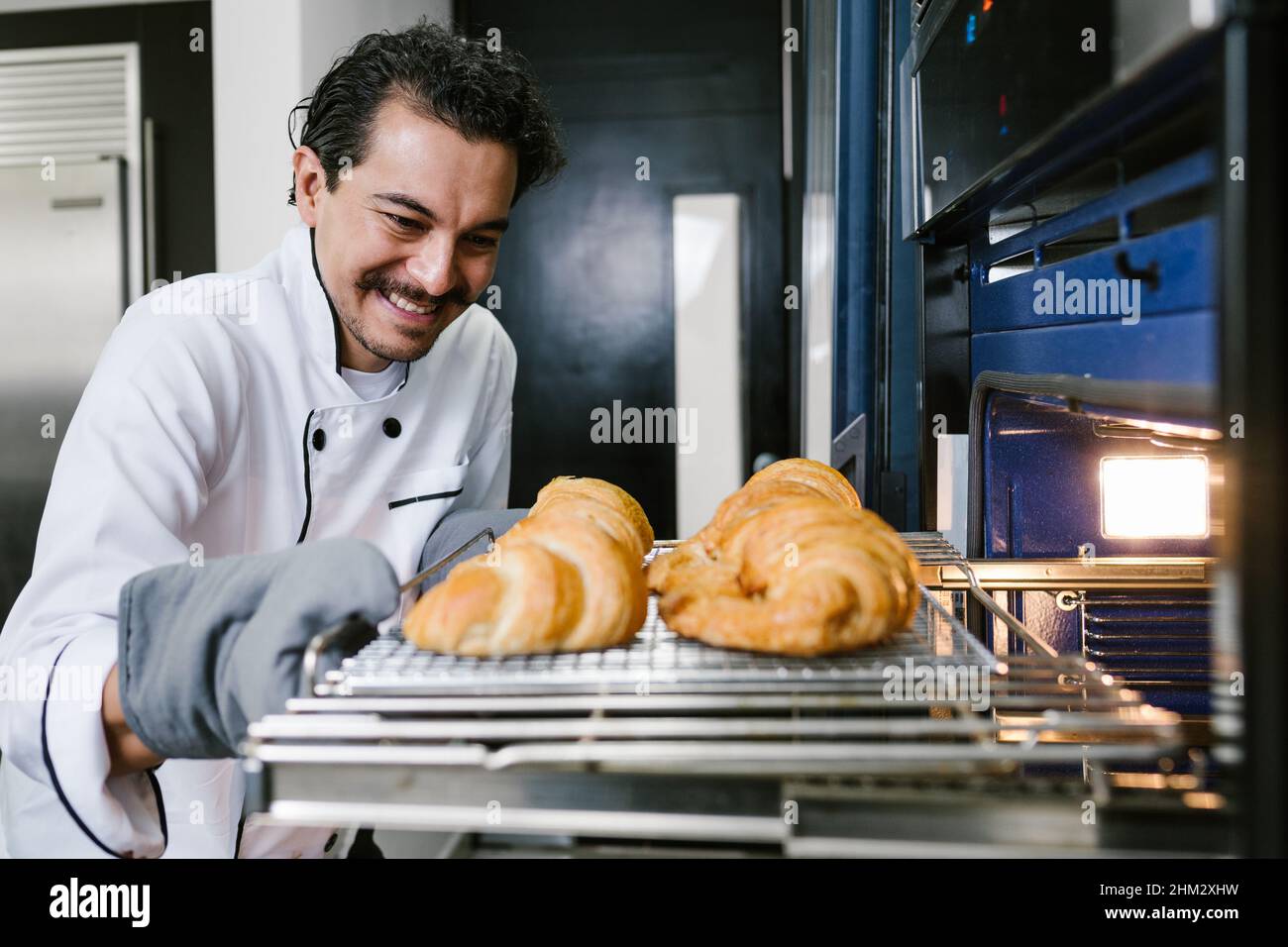Joven panadero latino y croissant de hornear y pan en horno en la cocina de  México América Latina Fotografía de stock - Alamy