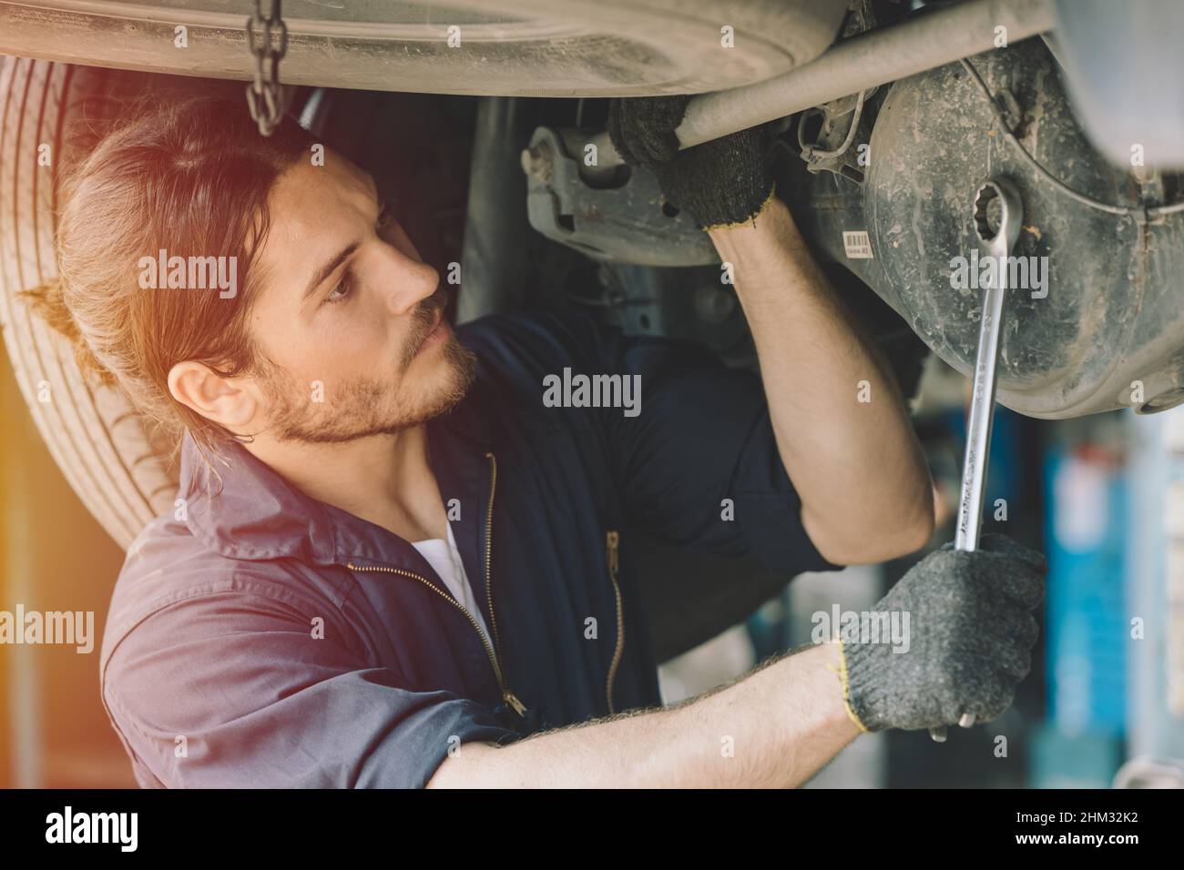 Caucasion hombre mecánico trabajador de servicio de coches que trabaja en el garaje reparar el problema del eje de transmisión Foto de stock