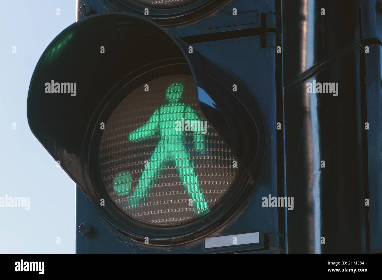 Concepto de fútbol, hombre de semáforo peatonal pateando una pelota, enfoque selectivo Foto de stock