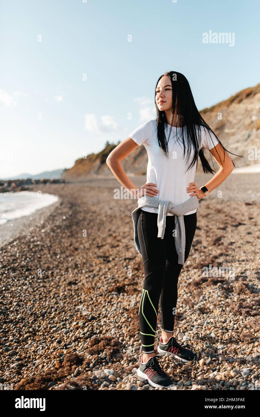 Concepto de deporte y estilo de vida saludable. Una mujer joven en ropa  deportiva, posando en una playa rocosa y mirando a la distancia. Vertcical  Fotografía de stock - Alamy