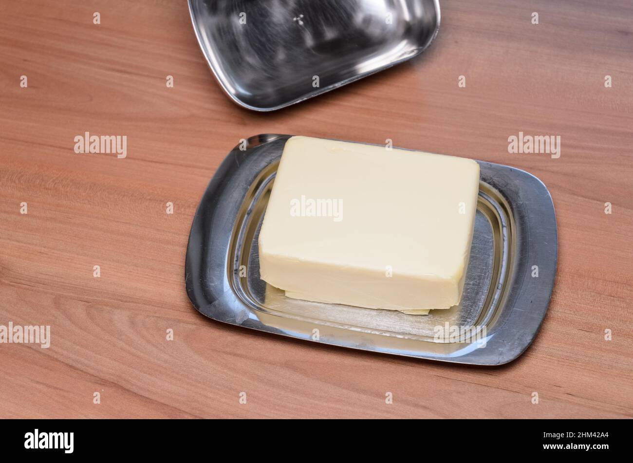 Plato de mantequilla de metal en el escritorio de madera en la cocina, vista desde arriba Foto de stock