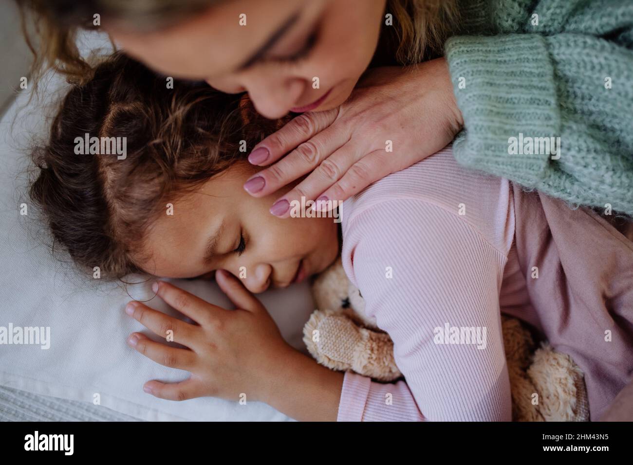 Primer plano de la madre cuidando a su hija enferma en casa. Foto de stock