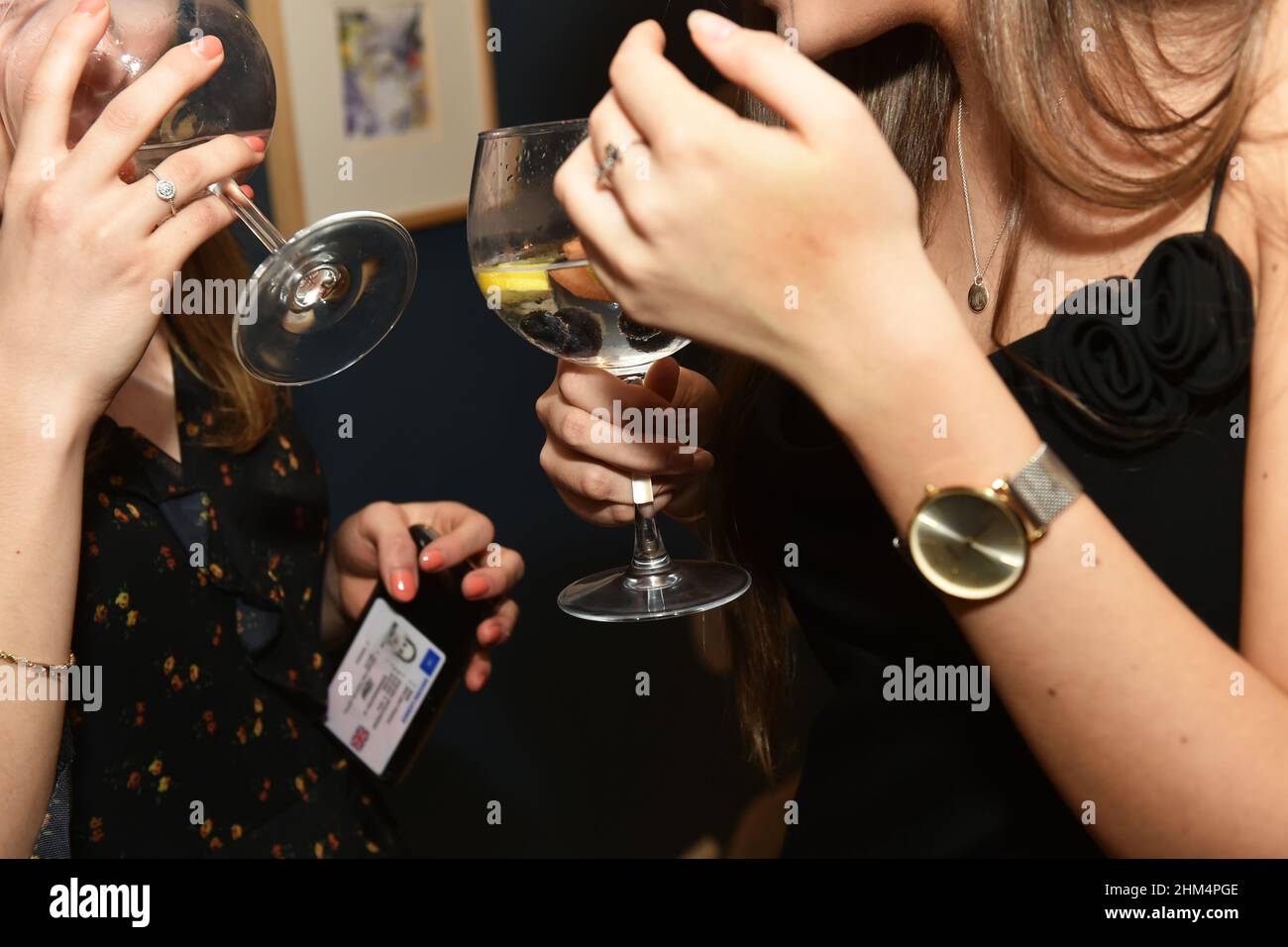 Una mujer joven bebe ginebra en una noche fuera, con identificación de edad Foto de stock