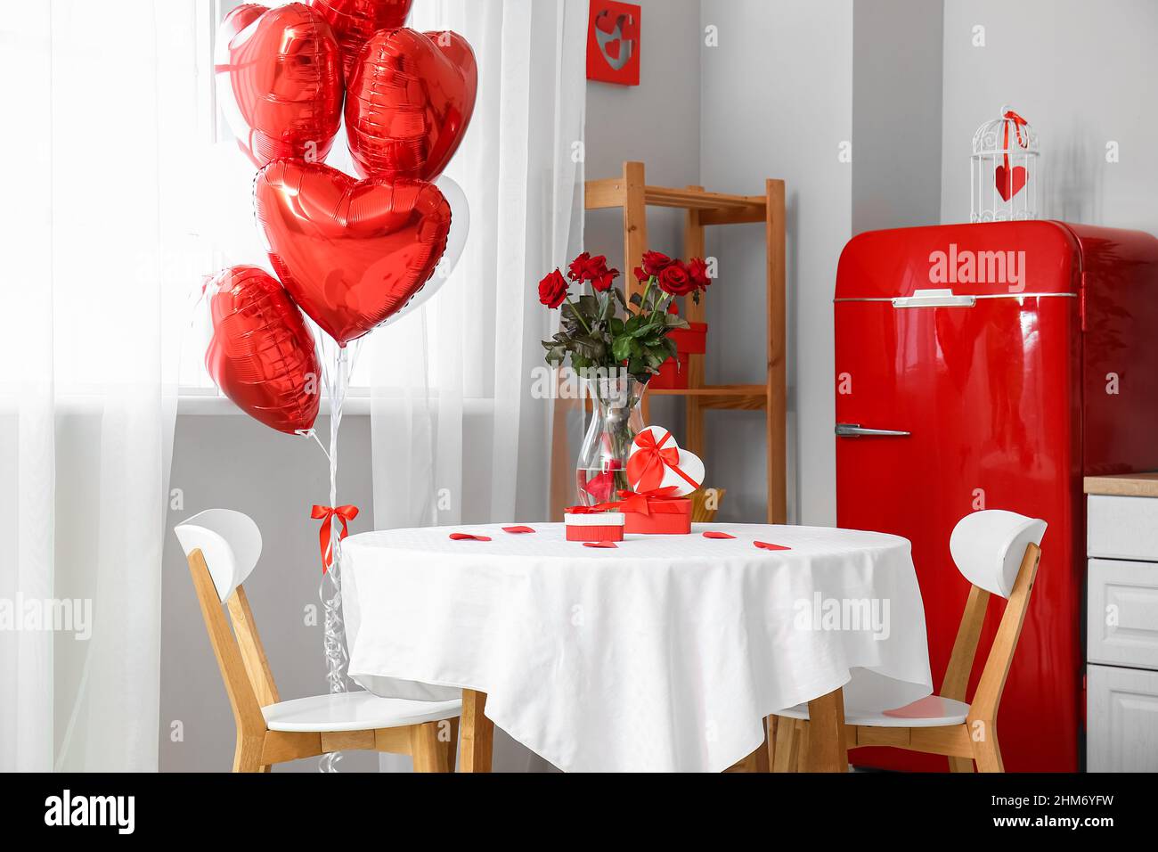 Mesa de comedor con rosas y cajas de regalo en cocina luminosa decorada  para la celebración del día de San Valentín Fotografía de stock - Alamy