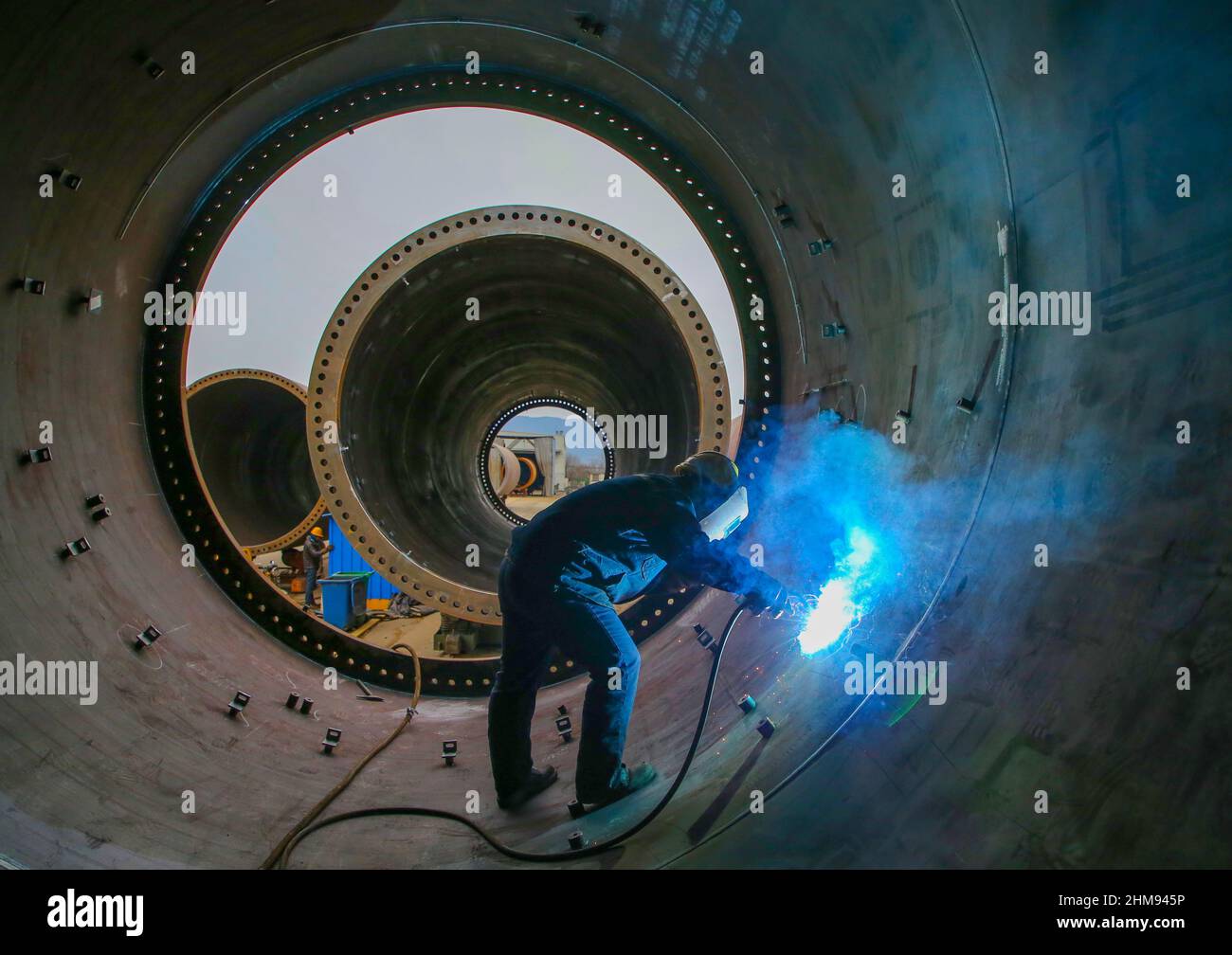 LIANYUNGANG, CHINA - 8 DE FEBRERO de 2022 - Un trabajador produce una torre de viento en un taller de Chongshan Wind Equipment Company en Lianyungang Economic and T Foto de stock