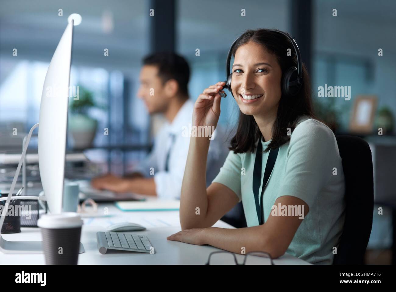 Te escucho. Retrato de una mujer joven utilizando un auricular y un ordenador en una oficina moderna. Foto de stock