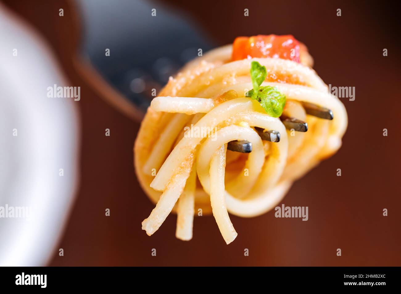 Pasta fresca con espagueti, tomate, champiñones, albahaca y queso parmesano en plato blanco sobre fondo de madera con ingredientes de fondo Foto de stock