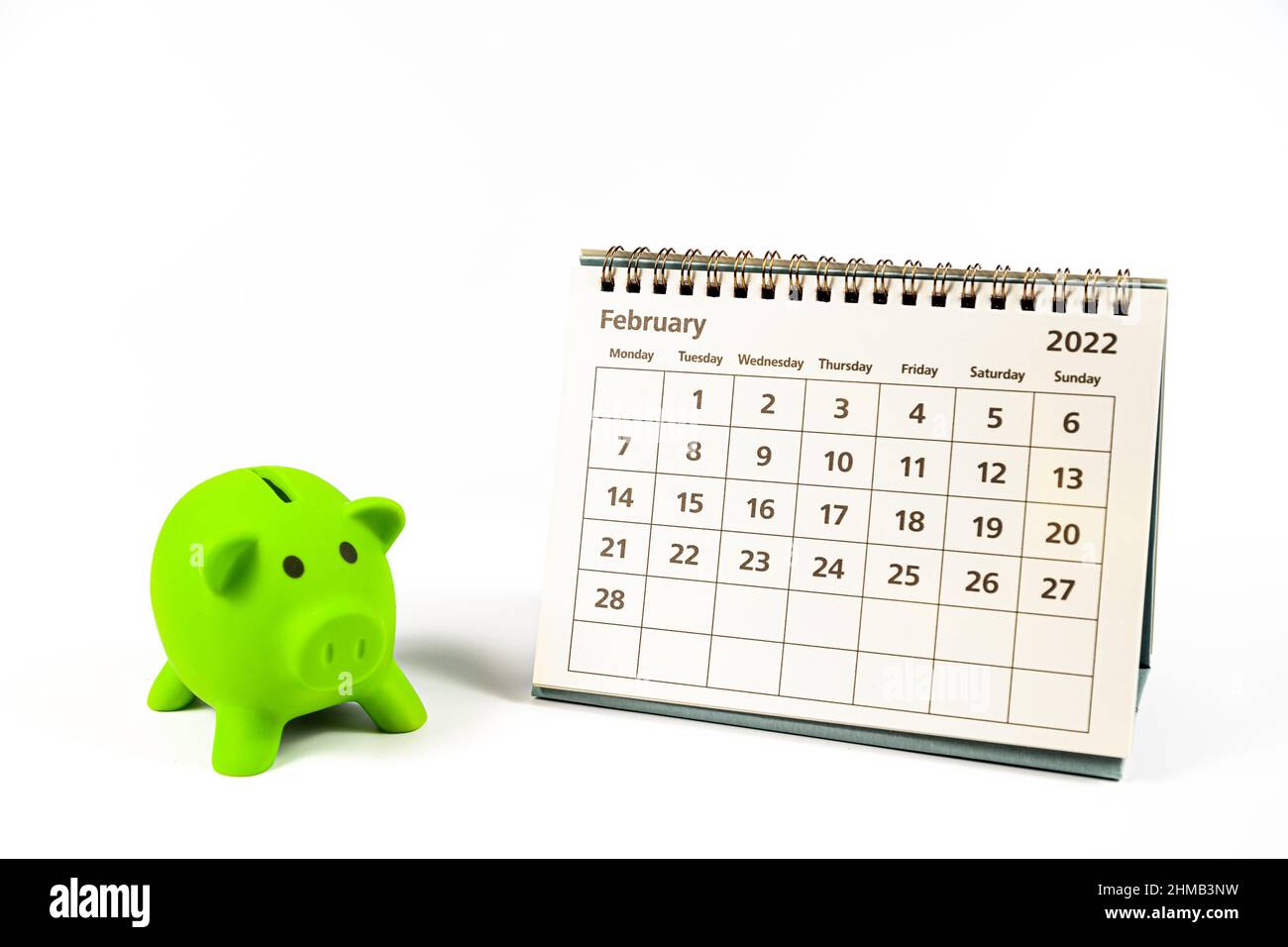 Calendario del 2022 de febrero y banco verde piggy sobre fondo blanco Foto de stock