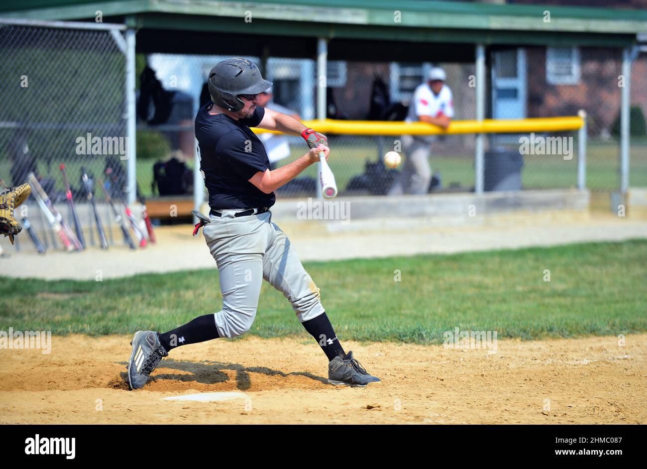 Johnsburg, Illinois, Estados Unidos. Un bateador balanceándose en un campo durante un partido de béisbol amateur masculino en el noreste de Illinois. Foto de stock