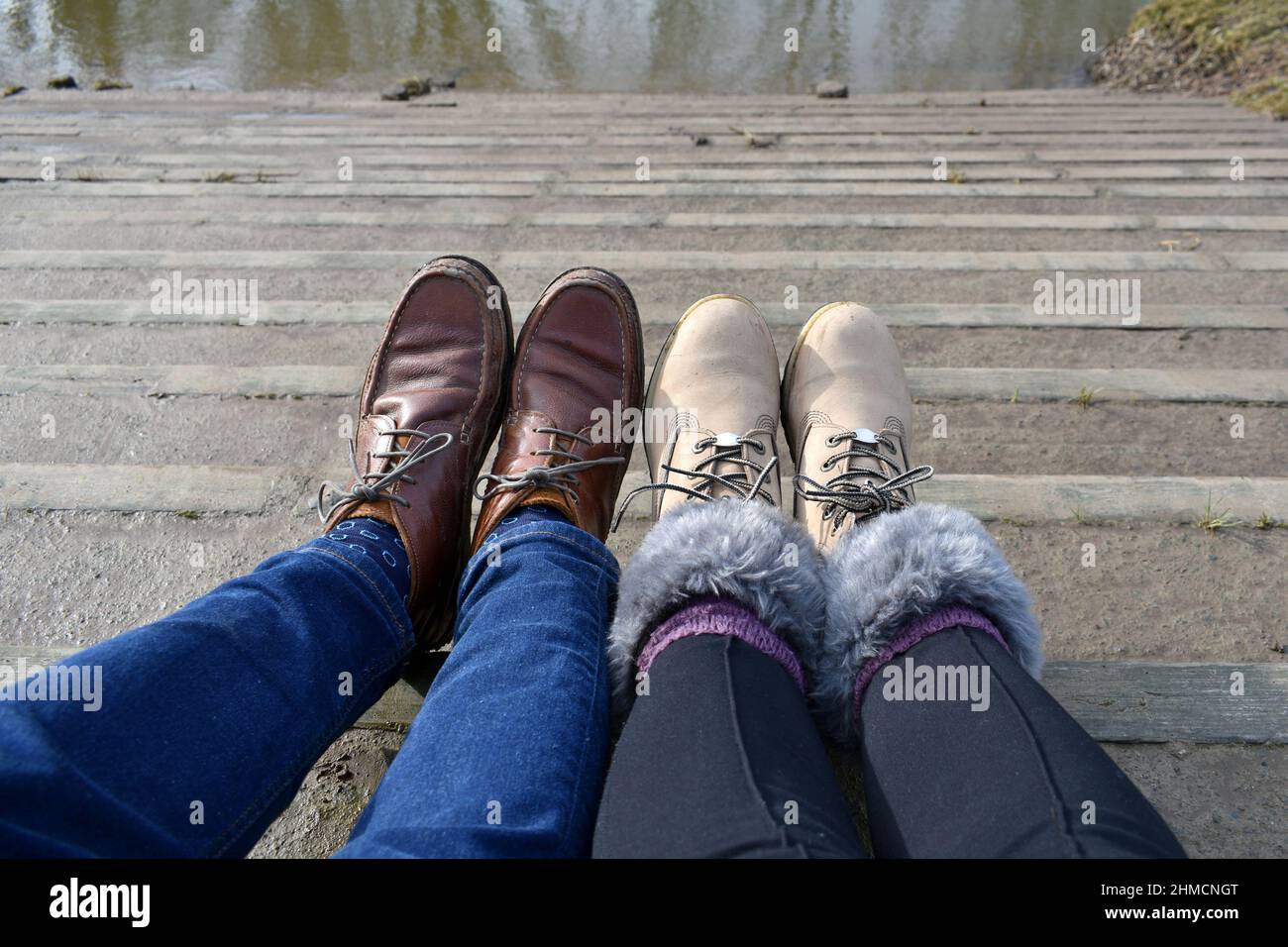 primer plano hombre y mujer pies con cordones para caminar botas en los  pasos mirando hacia abajo. Gente con los pies levantados, tomando un  descanso afuera en el sol del verano Fotografía
