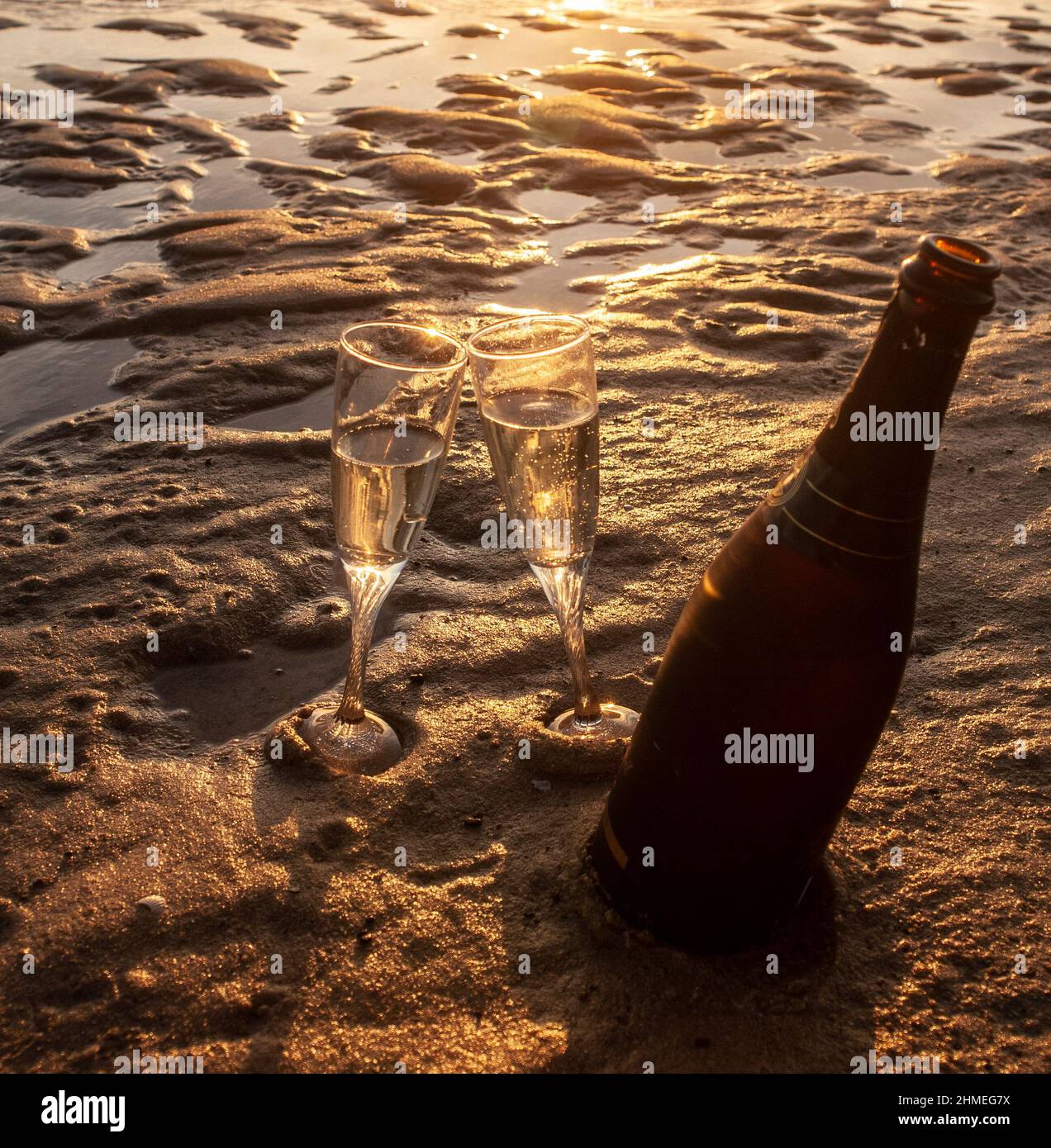 Dos capas con champán en la orilla de la playa de Tarifa al atardecer Foto de stock