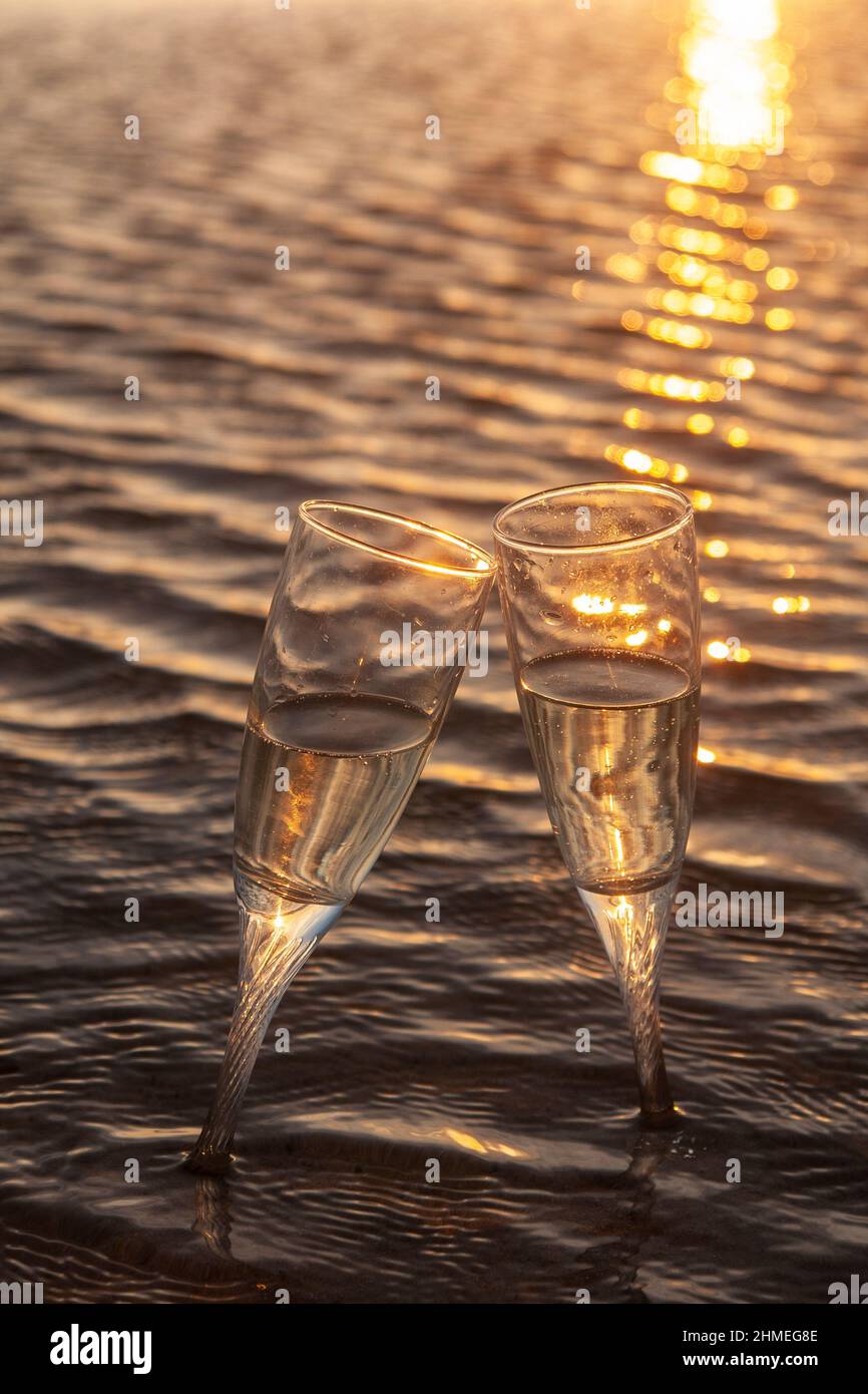 Dos capas con champán en la orilla de la playa de Tarifa al atardecer Foto de stock