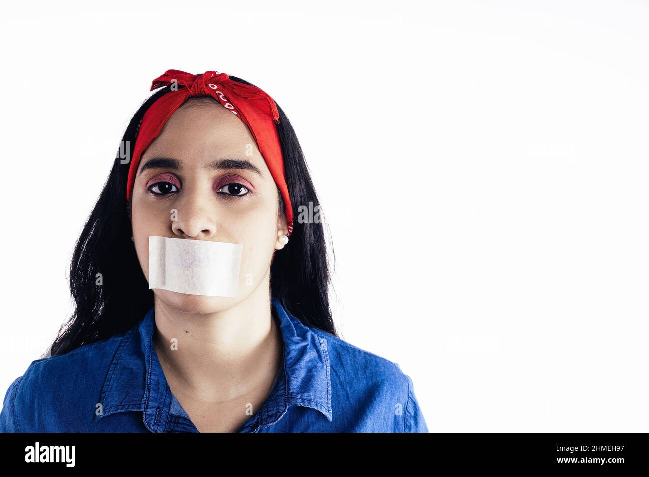 mujer hispana con cinta adhesiva en su boca concepto de feminismo, sobre fondo blanco. Foto de stock