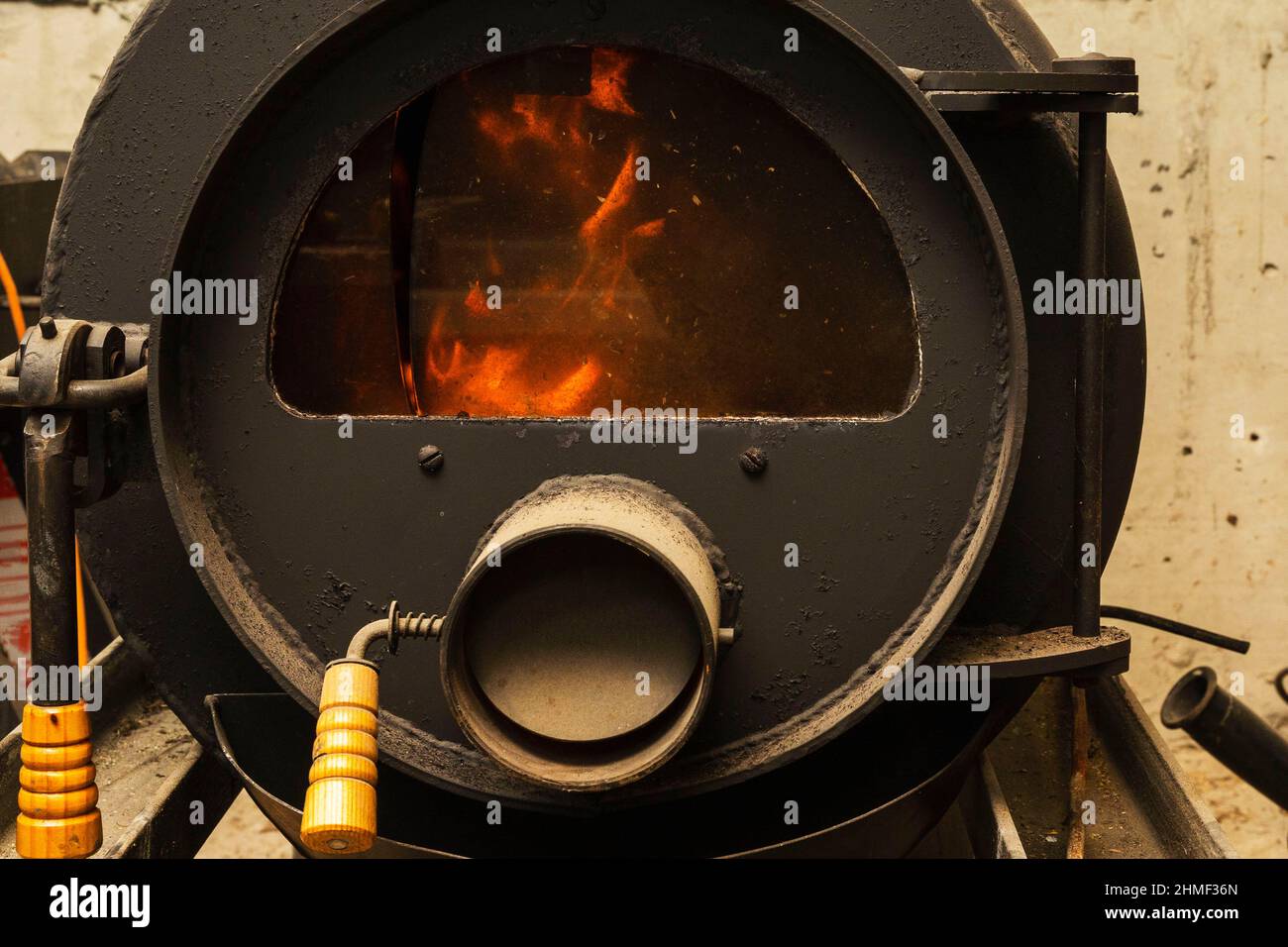 Estufa de hierro a leña para la quema a largo plazo, madera a leña detrás del vidrio refractario de la estufa gorenje. Foto de stock