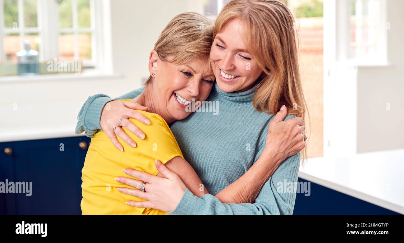 Mujer de la tercera edad Saludo y abrazando a la hija adulta adulta en el hogar Foto de stock