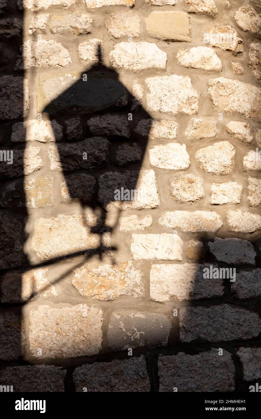 Croacia, bahía de Kvarner, isla de Krk, sombra de una farola en una pared de piedra, isla de Krk Foto de stock
