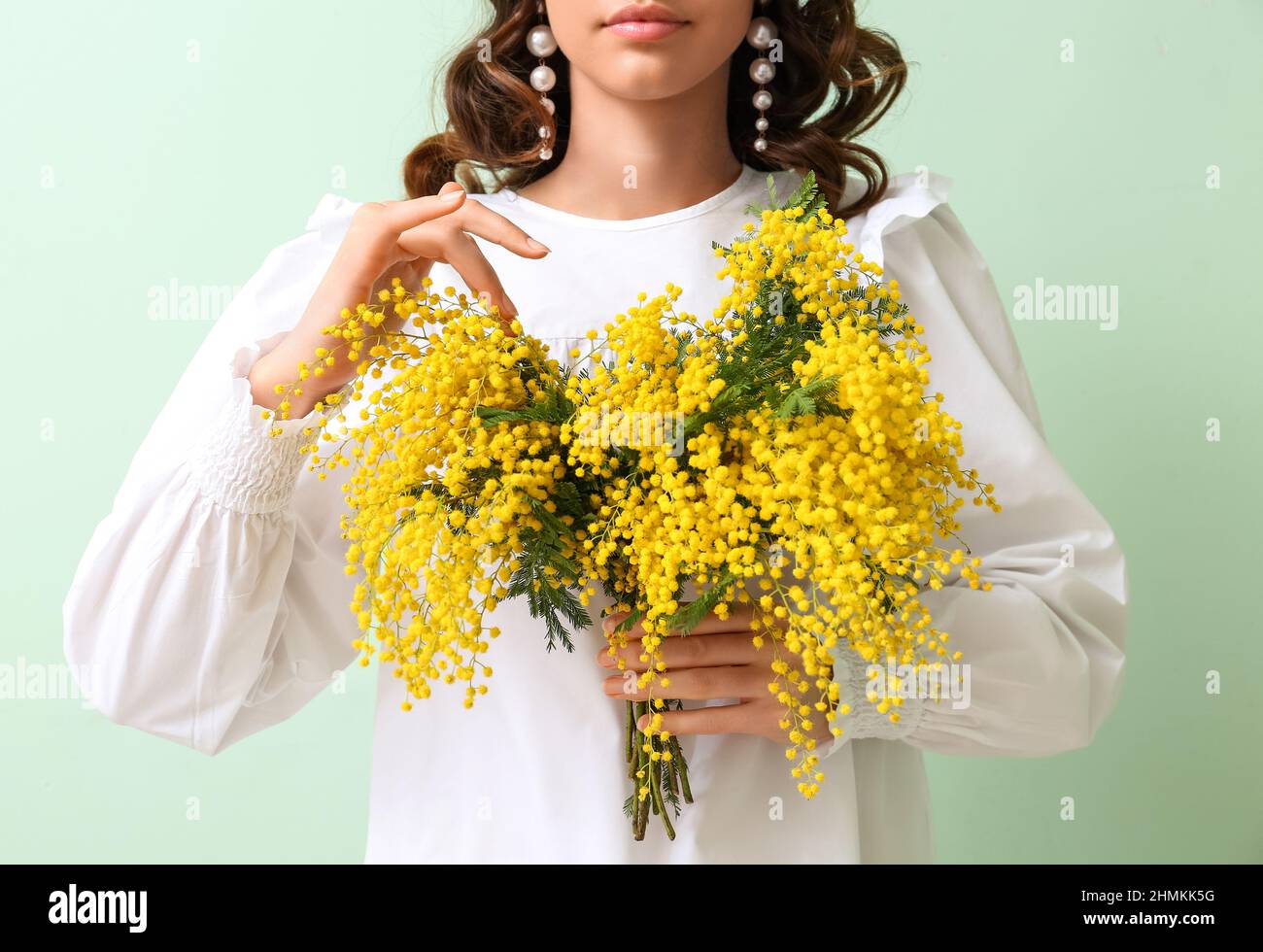 Hermosa mujer joven con ramo de flores mimosas sobre fondo verde Fotografía  de stock - Alamy