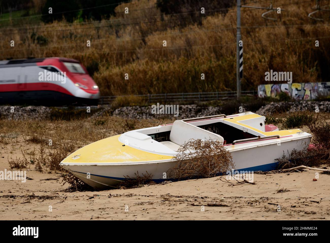 El tren pasa por un barco abandonado en la playa Foto de stock