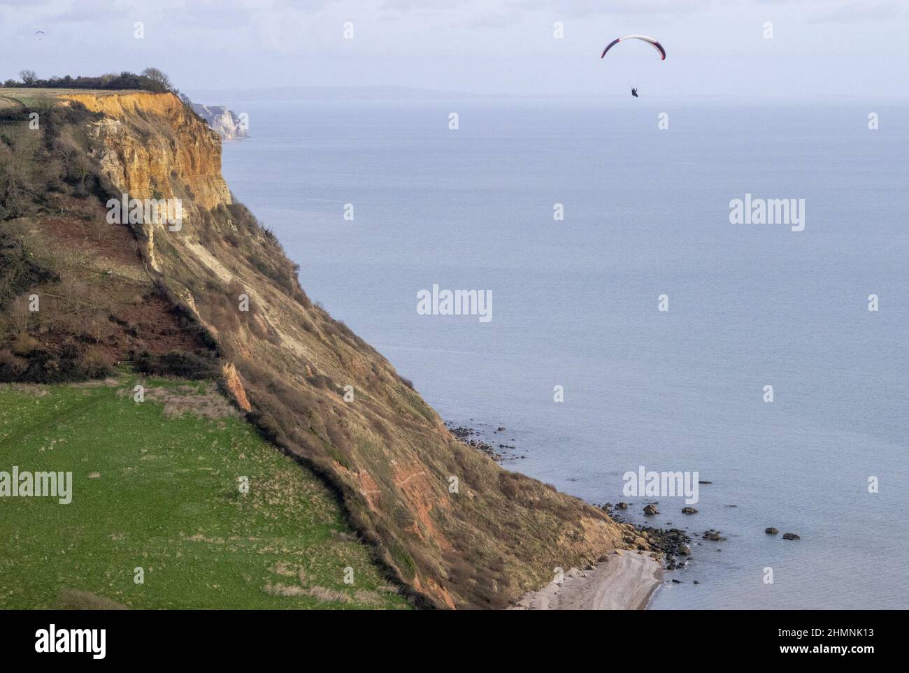 Sidmouth, Devon, 11th Feb 22 Un parapente aprovecha el clima cálido y quieto para volar sobre la boca de Salcombe, cerca de Sidmouth. Crédito: Photo Central/Alamy Live News Foto de stock