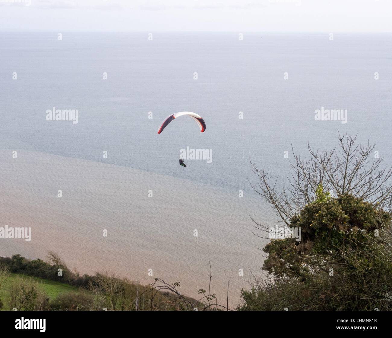 Sidmouth, Devon, 11th Feb 22 Un parapente aprovecha el clima cálido y quieto para volar sobre la boca de Salcombe, cerca de Sidmouth. Crédito: Photo Central/Alamy Live News Foto de stock