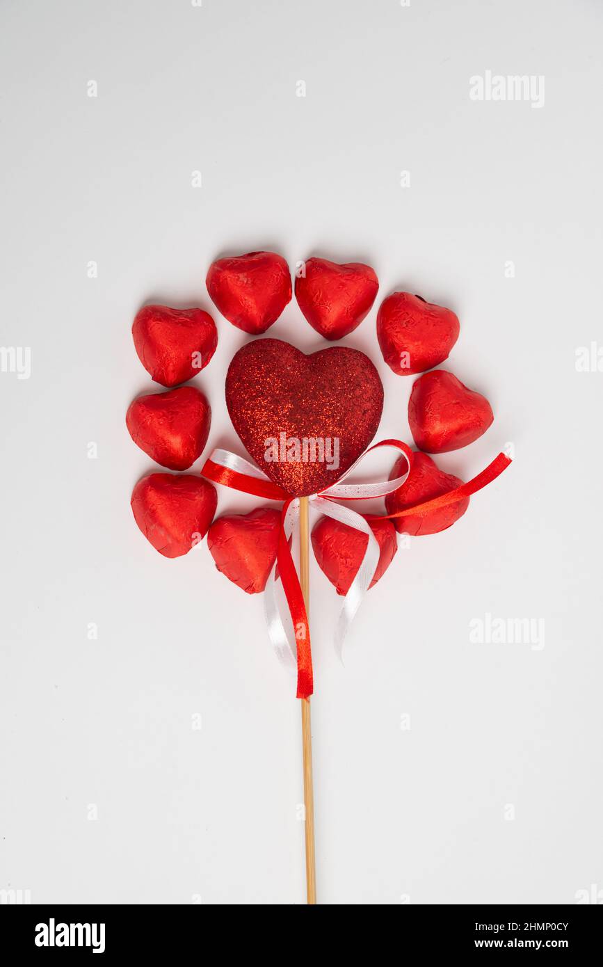 Dulces de corazón rojo chocolate para el día de San Valentín sobre un fondo  blanco en forma de círculo con una decoración de corazón en un poste de  madera en el medio