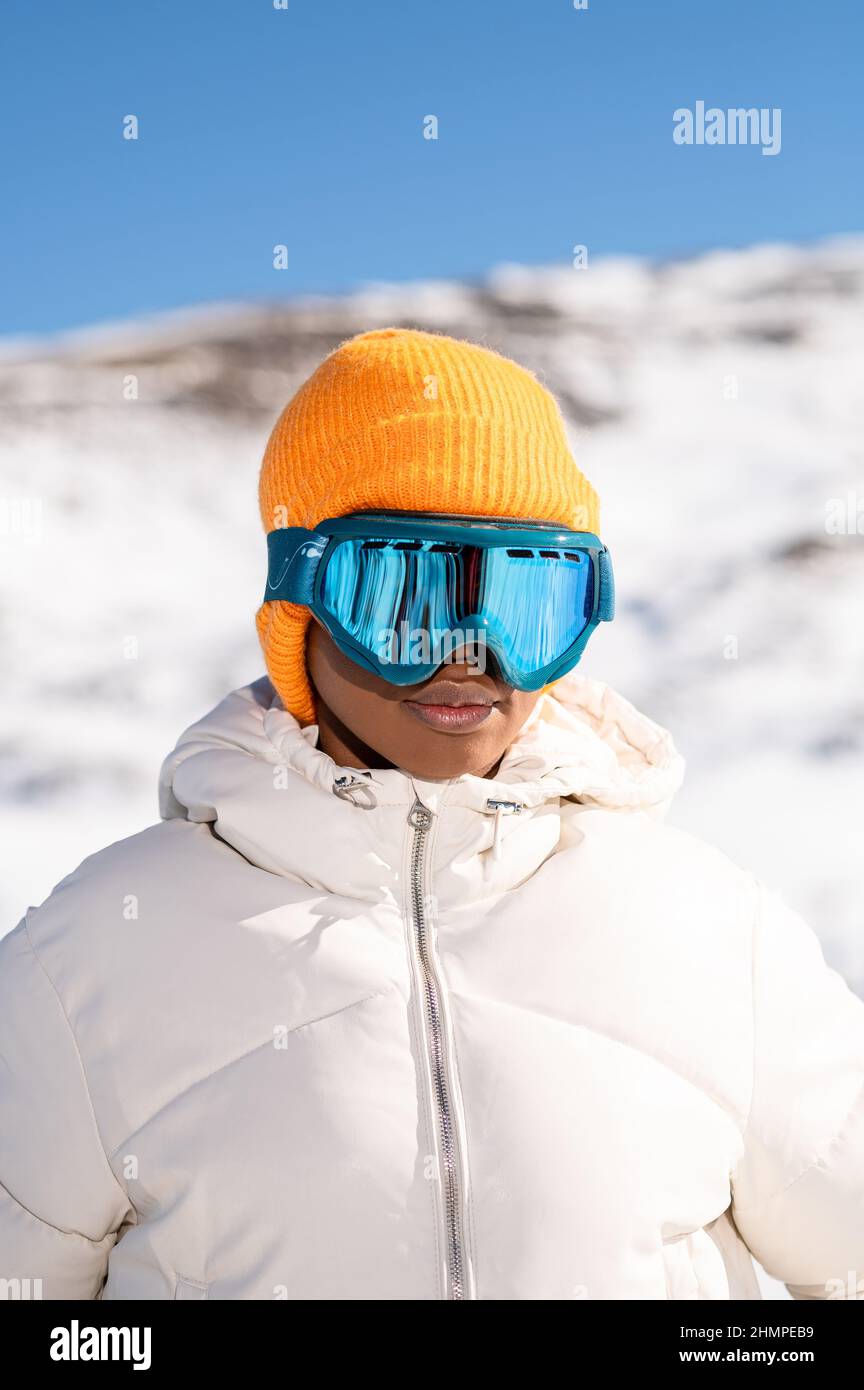 Mujer afroamericana que lleva gafas de pie en la montaña nevada durante el invierno Foto de stock