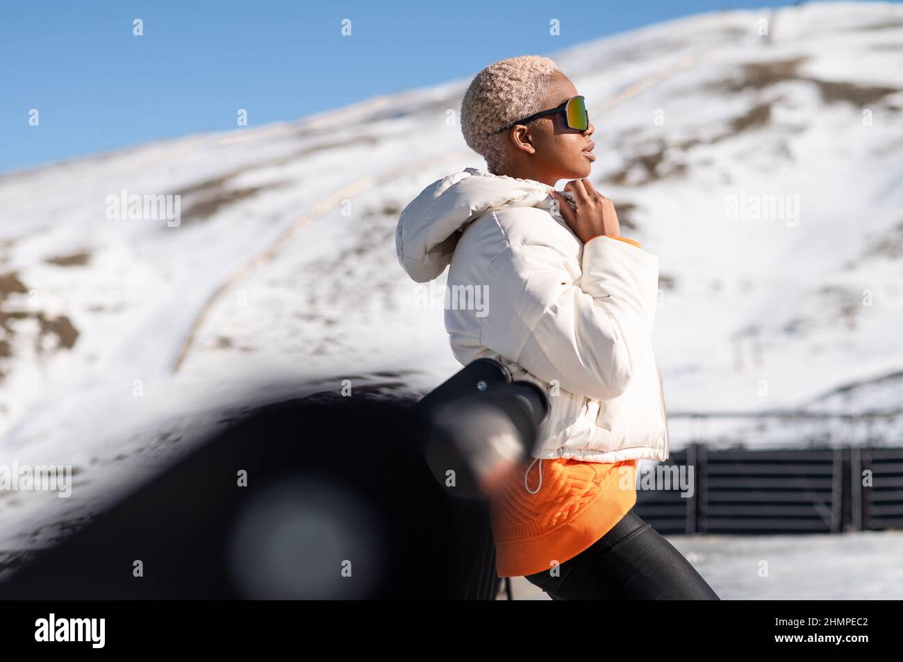 Mujer afroamericana que lleva gafas de pie en la montaña nevada durante el invierno Foto de stock