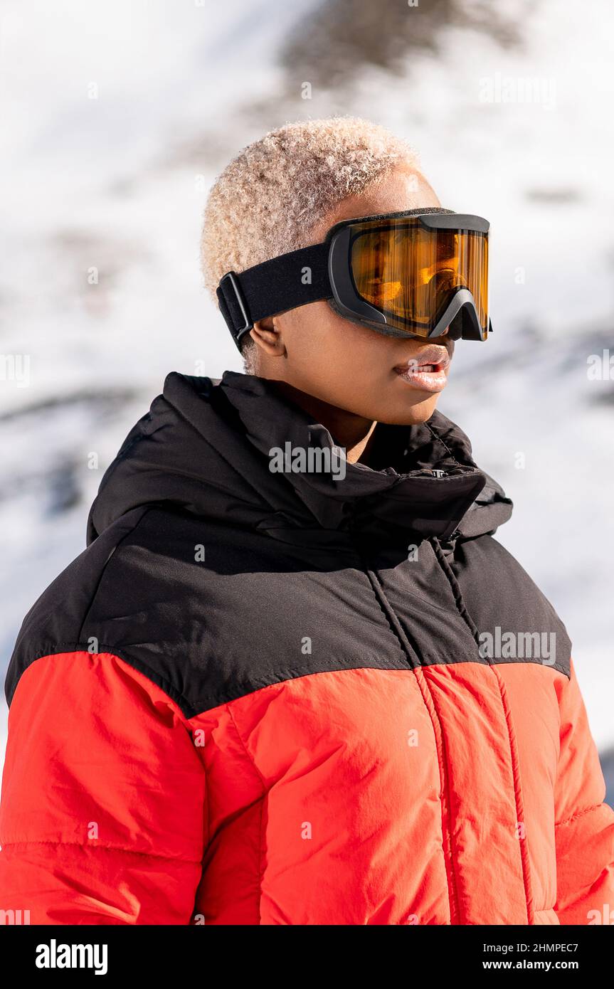 Mujer afroamericana que lleva gafas de pie en la montaña nevada durante el invierno Foto de stock