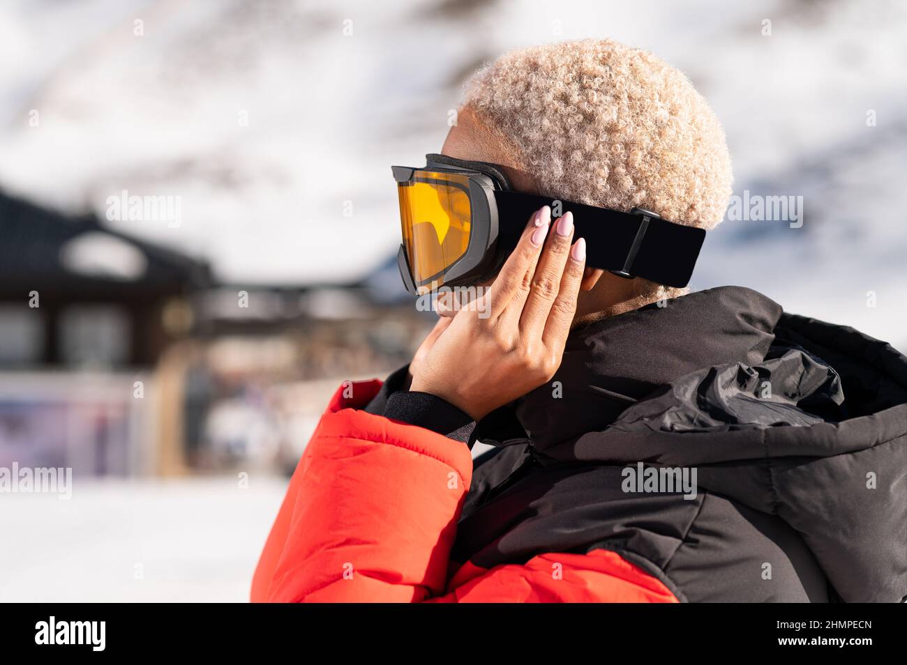 Una mujer afroamericana con gafas de nieve en una montaña nevada durante el  invierno