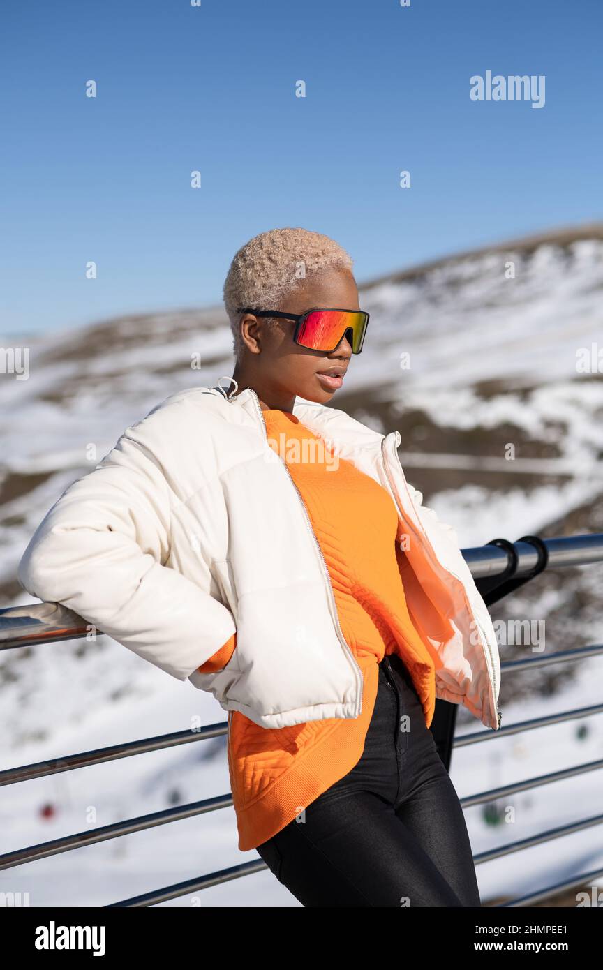 Una mujer afroamericana con gafas de nieve en una montaña nevada durante el  invierno