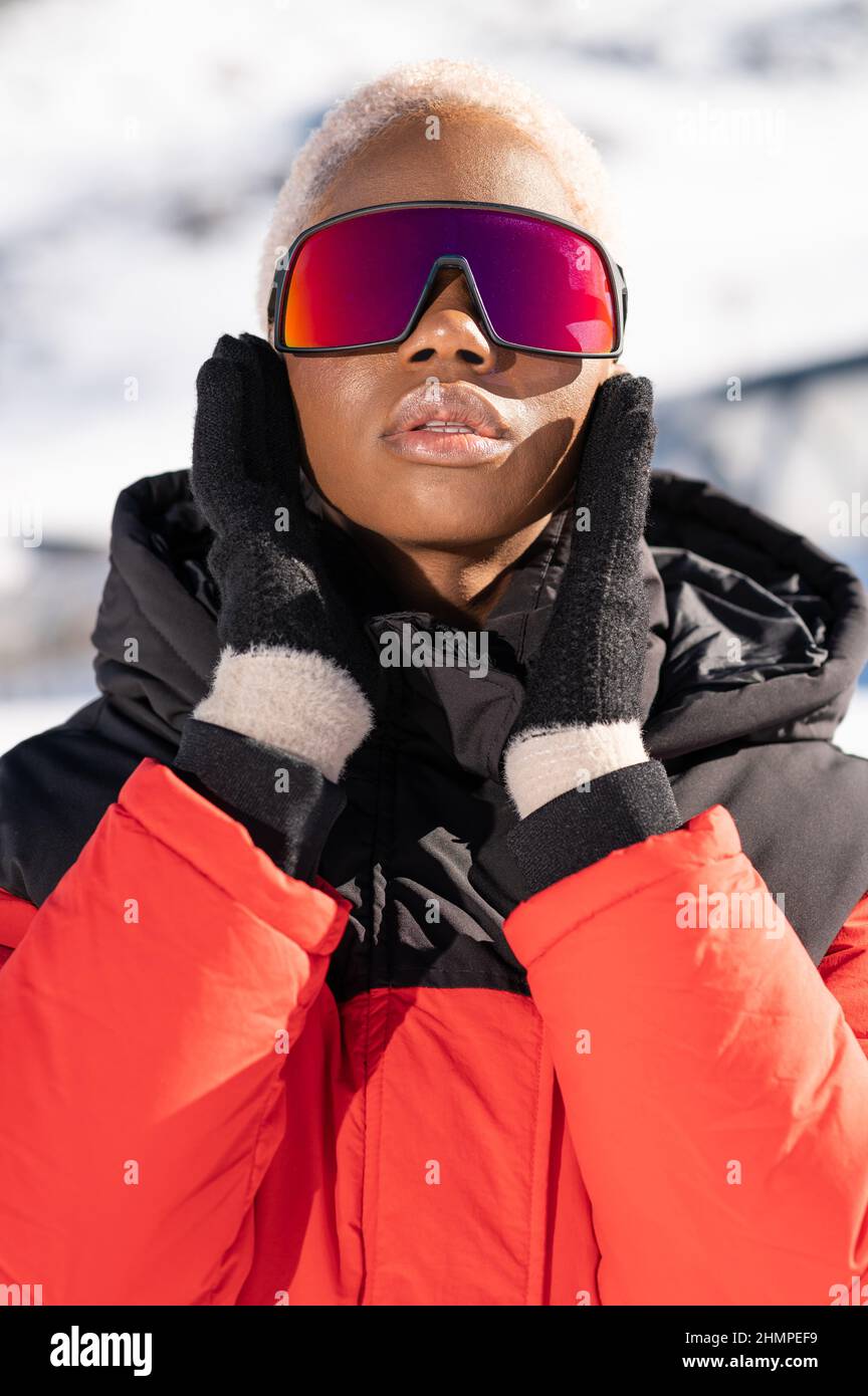 Una mujer afroamericana con gafas de nieve en una montaña nevada