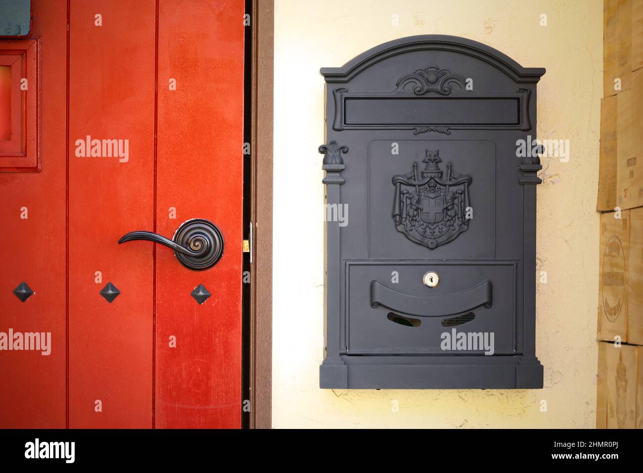 Entrada de estilo europeo antiguo con puertas de madera roja y buzón de hierro Foto de stock