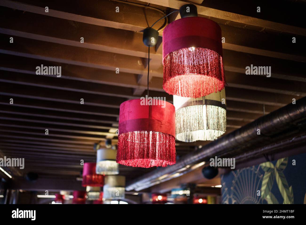 Interior de un moderno restaurante con lámparas de araña colgadas de un techo de vigas de madera. Foto de stock
