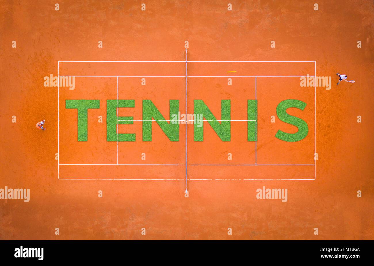 Pista de tenis de arena naranja con dos jugadores jugando desde arriba con letras hechas de hierba Foto de stock