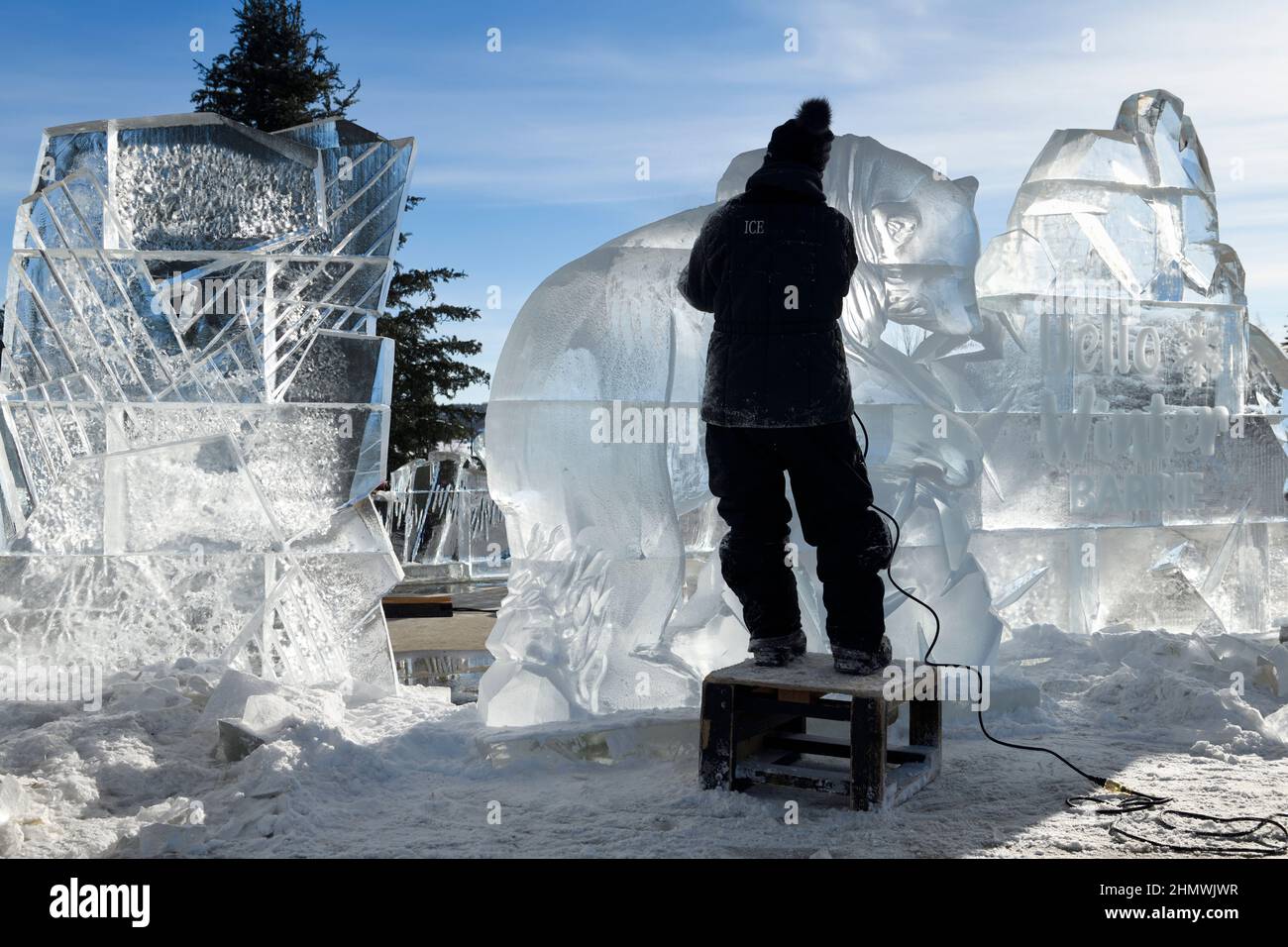 Escultora femenina que trabaja en la talla de una escultura de hielo de un oso polar en Meridian Place en Barrie en Winterfest 2022 llamada Hello Winter Foto de stock