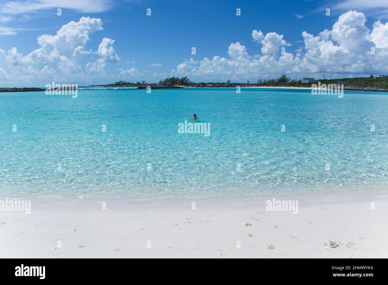 Hermosa vista del hombre flotando en la playa en el océano Atlántico con arena blanca en las islas Bahamas. Foto de stock