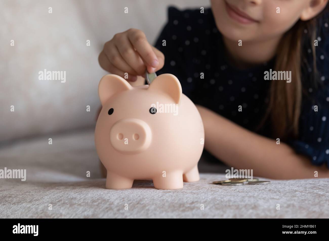 Niño cayendo moneda en el juguete rosa piggybank Foto de stock