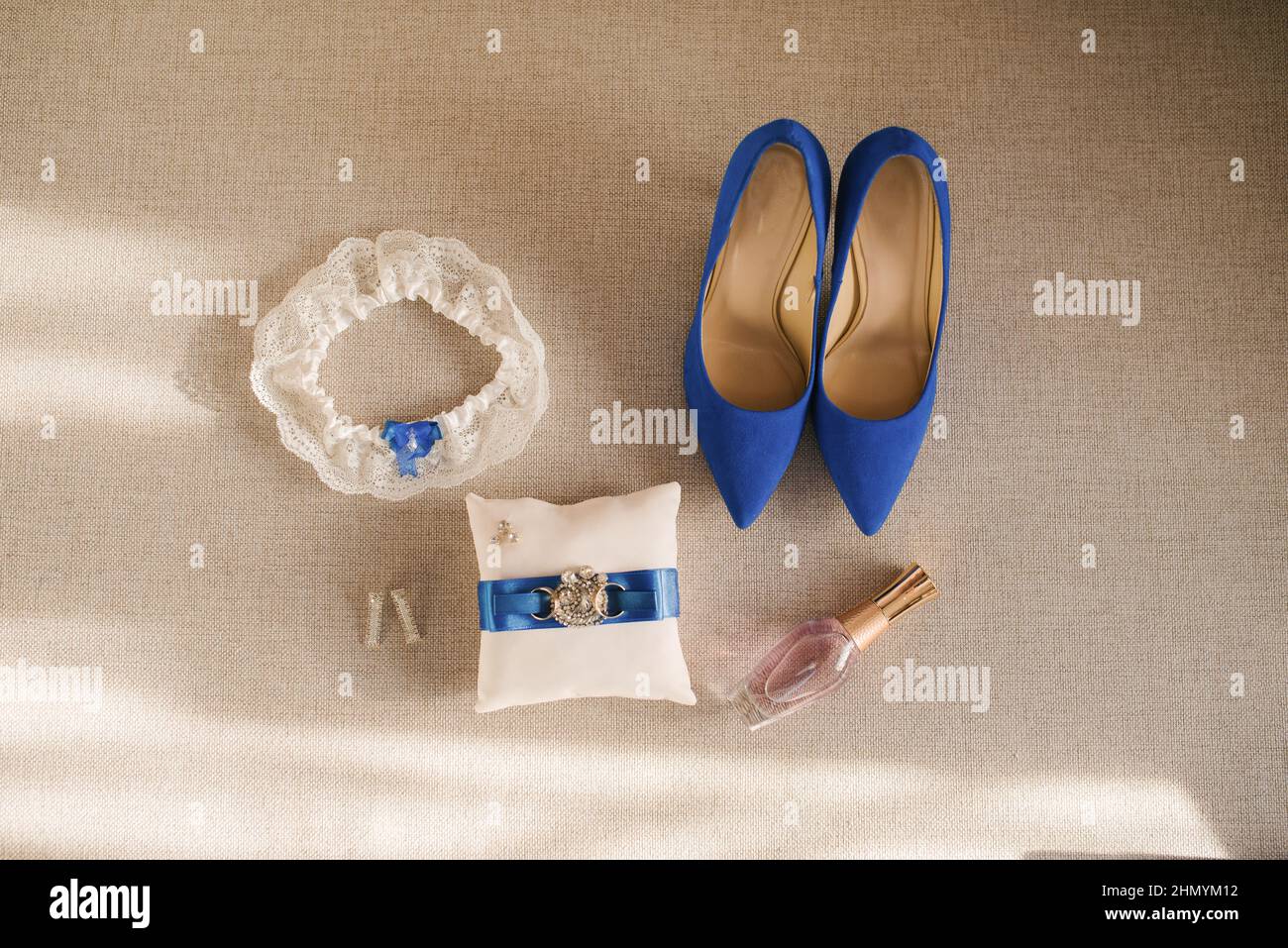 Los accesorios para bodas de la novia son blancos y azules: Zapatos, cojín de anillo, perfume, liga y pendientes Foto de stock