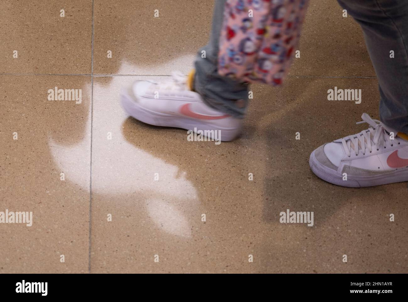 Hong Kong, China. 12th Feb, 2022. Un comprador que lleva zapatillas Nike  pasa por delante de la multinacional tecnológica estadounidense Apple Store  y el logotipo se refleja en el suelo de Hong