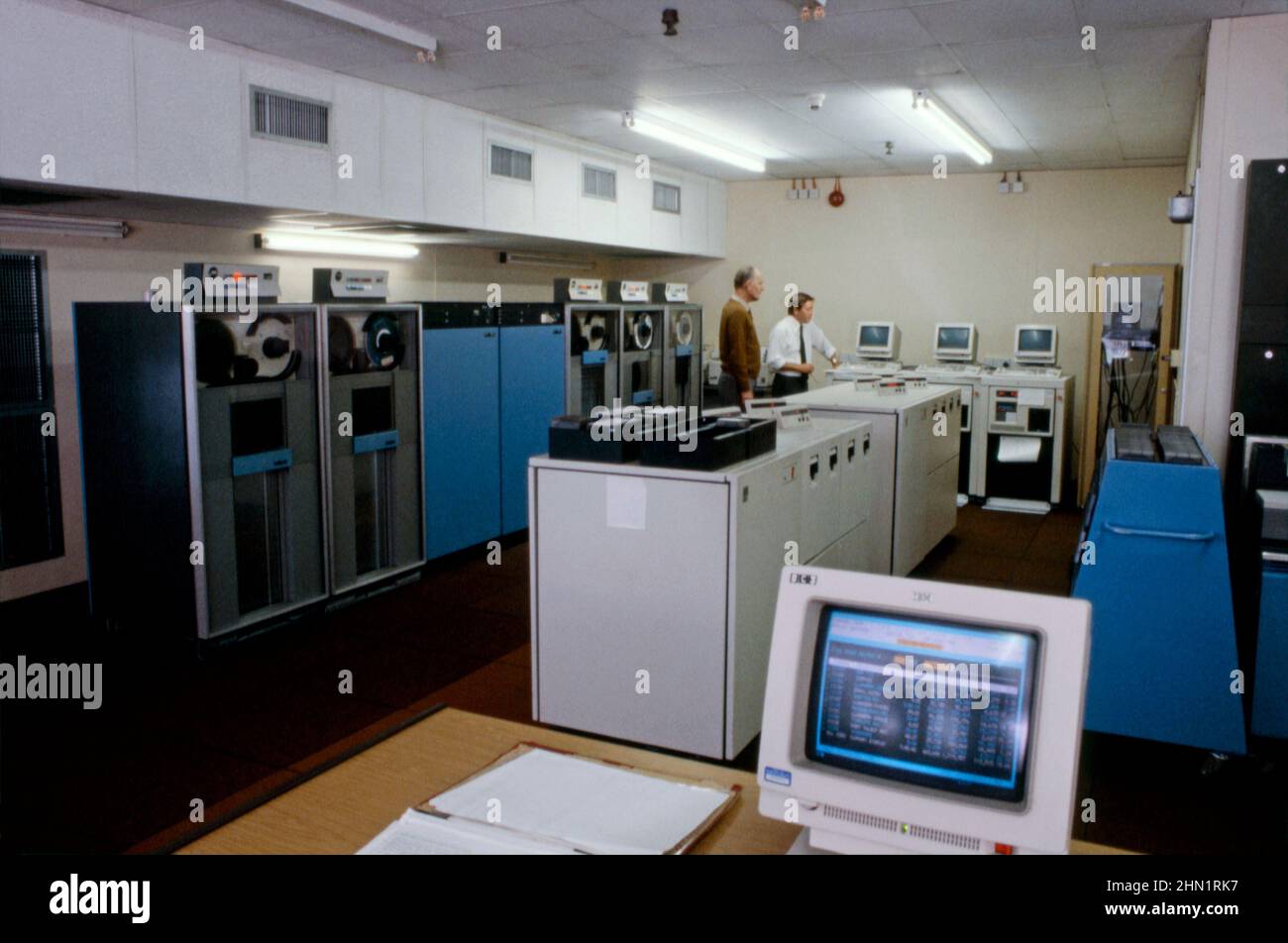 Una vista de mediados de 1980s dentro de Port Talbot Steelworks, una planta integrada de producción de acero en Port Talbot, West Glamorgan, Gales, Reino Unido. Vista de la sala de ordenadores de la empresa. Los grandes ordenadores mainframe estaban empezando a desempeñar un papel importante en la industria en este momento. Aparece una pantalla de IBM en primer plano. Los portátiles y las tabletas ahora tienen la potencia y la velocidad de procesamiento necesarias para sustituir a los equipos antiguos, ya de gran tamaño y que ya no eran tan antiguos. Esta imagen es de una transparencia de color vintage: Una fotografía vintage 1980s. Foto de stock