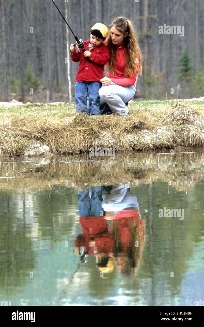 Madre ayudando a su joven hijo peces en un estanque cerca de West Glacier, MT Foto de stock