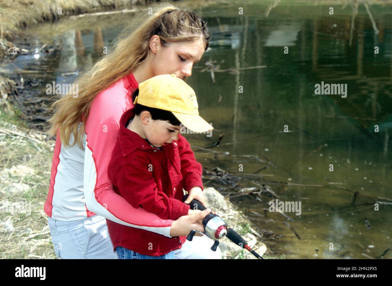 Madre enseñando a su hijo joven cómo pescar en un lago de Montana Foto de stock