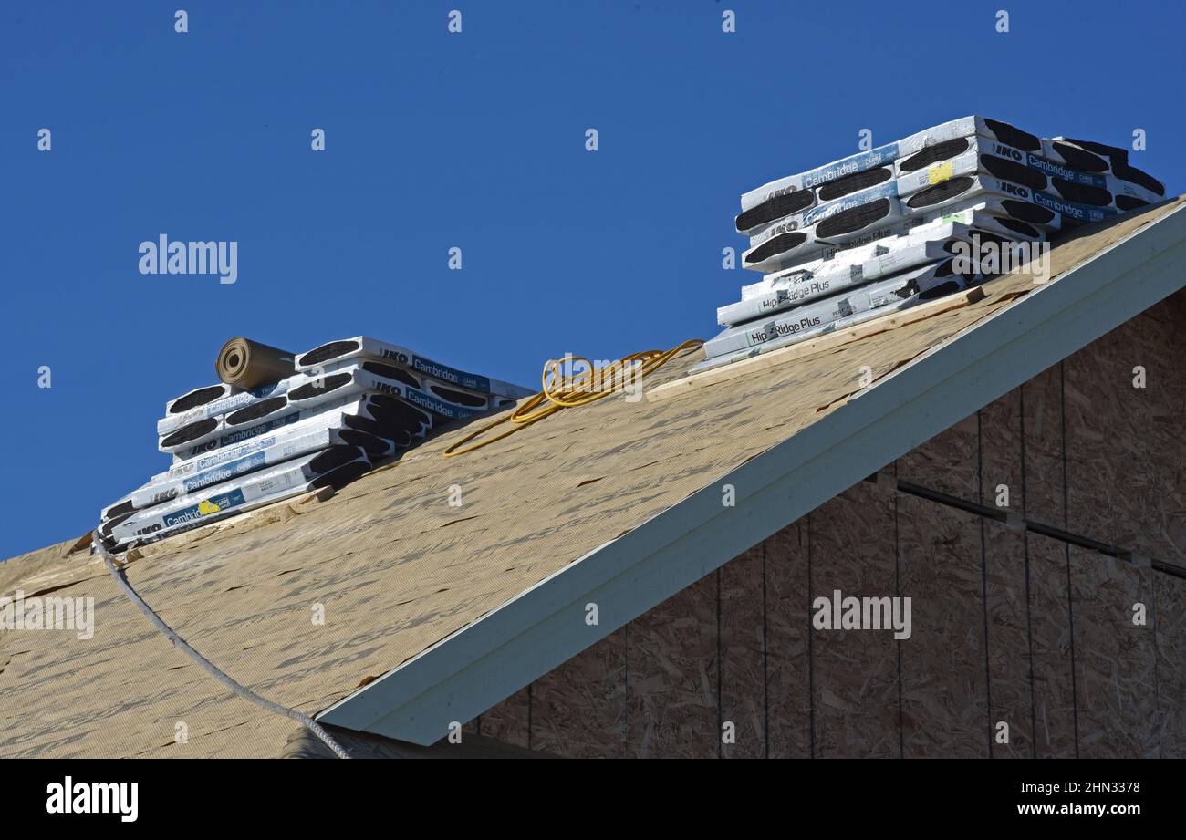 Se apila un montón de tejas en el techo de una casa en construcción en una nueva subdivisión residencial en Langford, British Columbia, Canadá Foto de stock