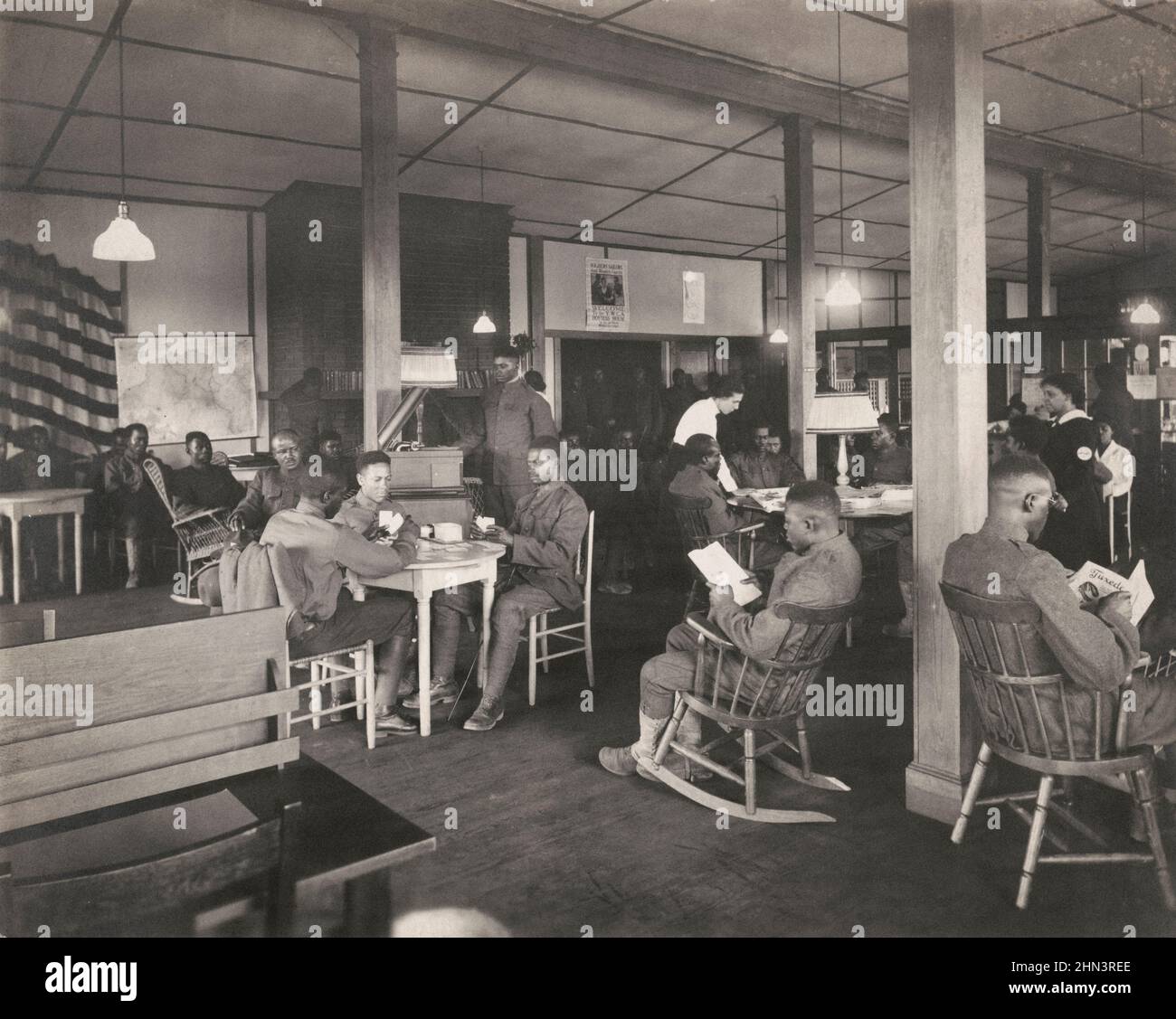 Foto vintage de los soldados afroamericanos leyendo, jugando a las cartas y relajándose en Y.W.C.A. Casa de la anfitriona. 1918 Foto de stock