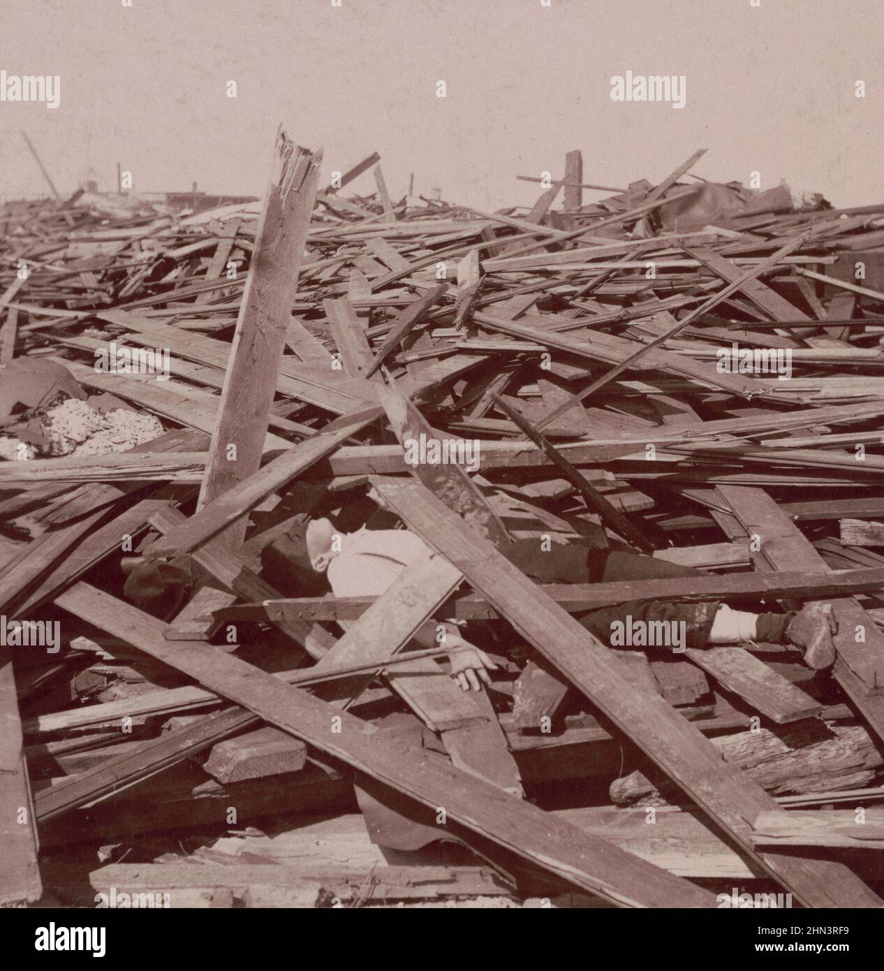 Foto vintage de Galveston Disaster, un hombre muerto bajo una vasta pila de tablones de madera después del huracán Galveston de 1900. EE.UU Foto de stock