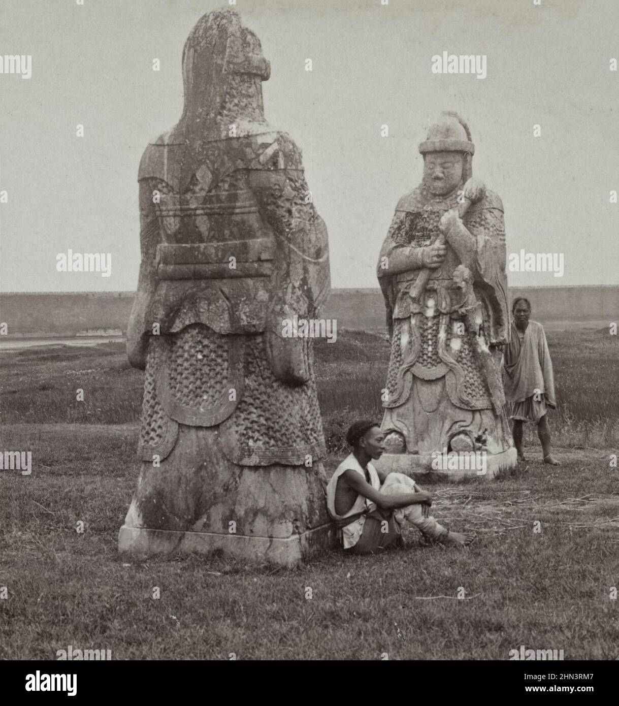 Foto vintage de los hombres chinos con vestimenta tradicional y cola cerca de una enorme figura de piedra en la avenida que conduce a las Tumbas de los Reyes (Tumbas Ming). Na Foto de stock