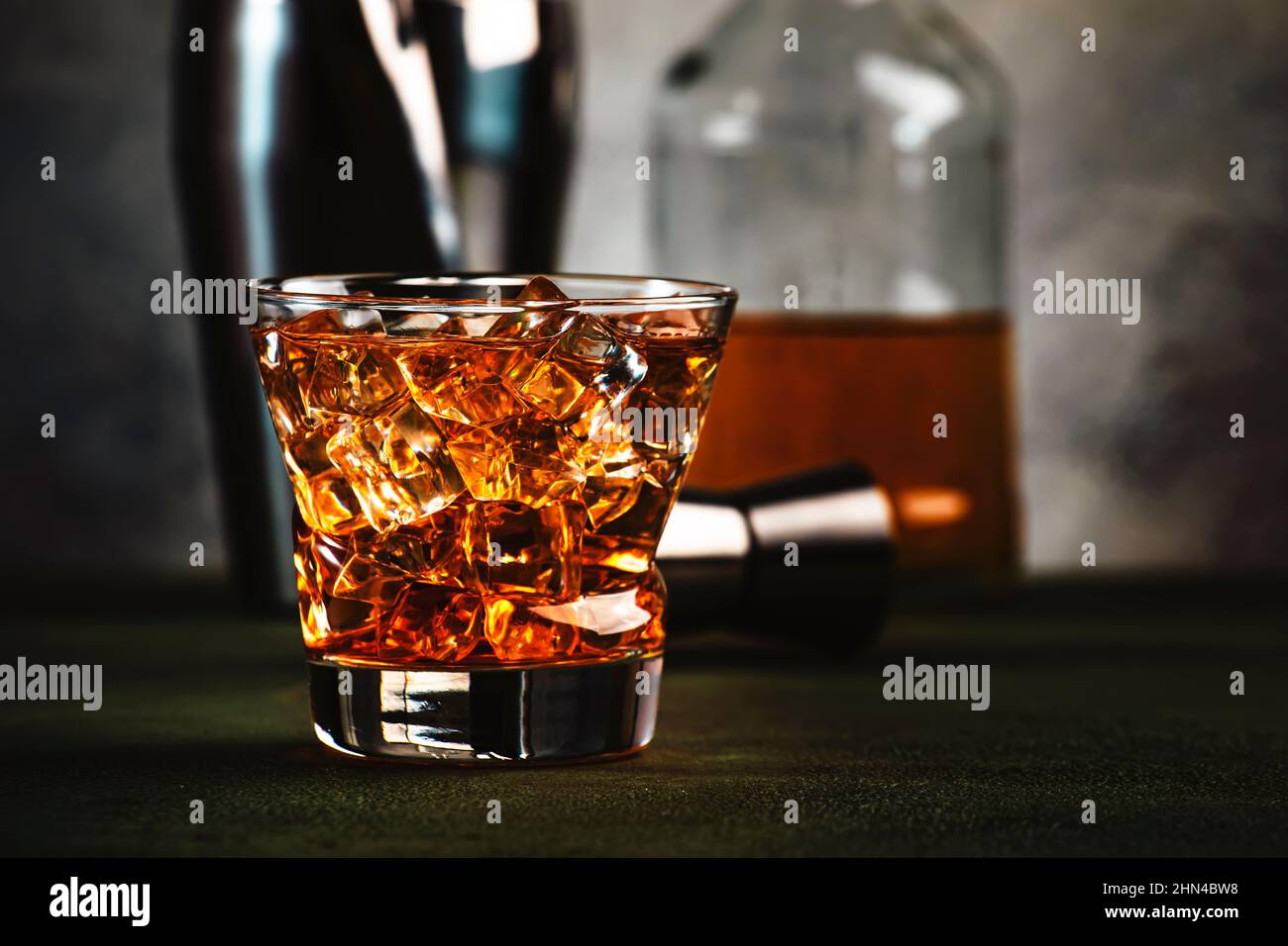 Cóctel alcohólico padrino con whisky escocés, licor de amaretto hielo. Fondo de barra oscura, herramientas de barra, espacio de copia Fotografía de stock Alamy