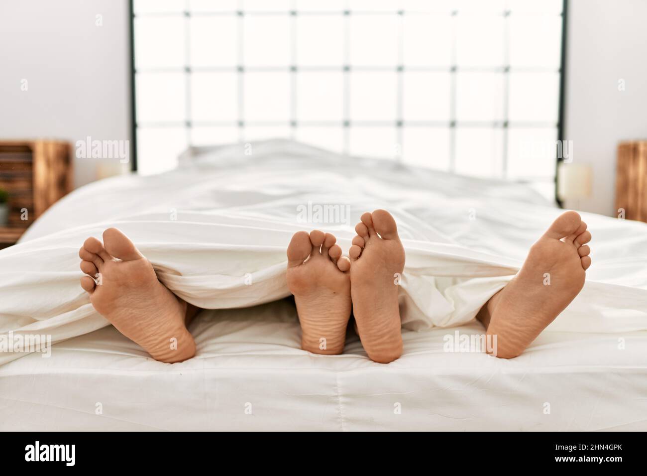 Dos parejas de hombres hispanos tumbados en la cama en el dormitorio  Fotografía de stock - Alamy